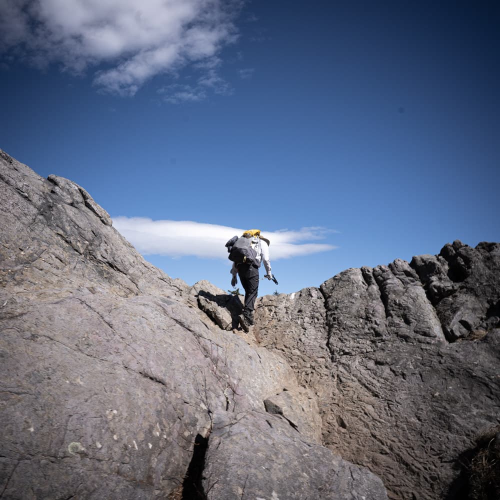 A backpacker scrambles over a rocky surface