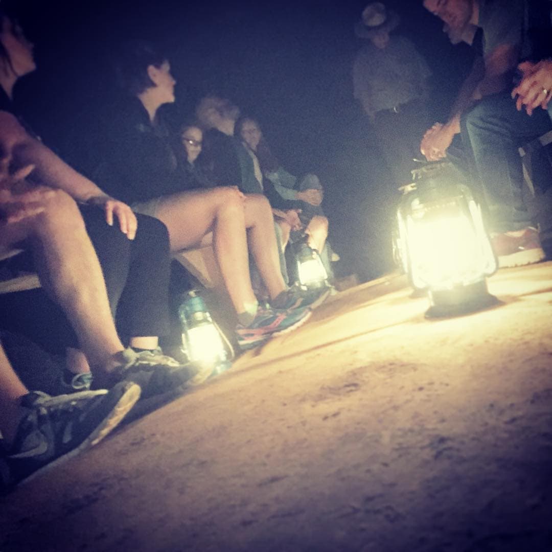 Oil lamp illuminating a group on a bench in a dark cave