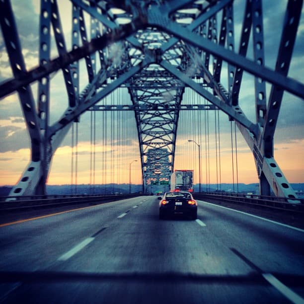 Cars moving across a bridge with a dramatic evening sunset