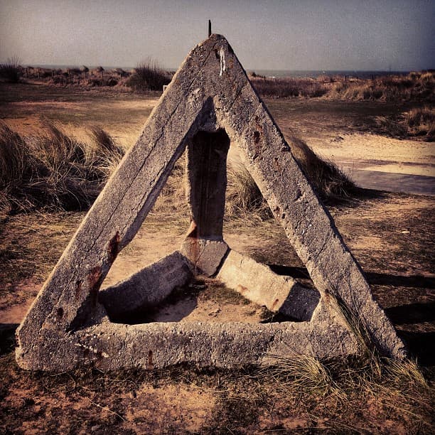 Concrete triangle on a beach in the suns warm glow
