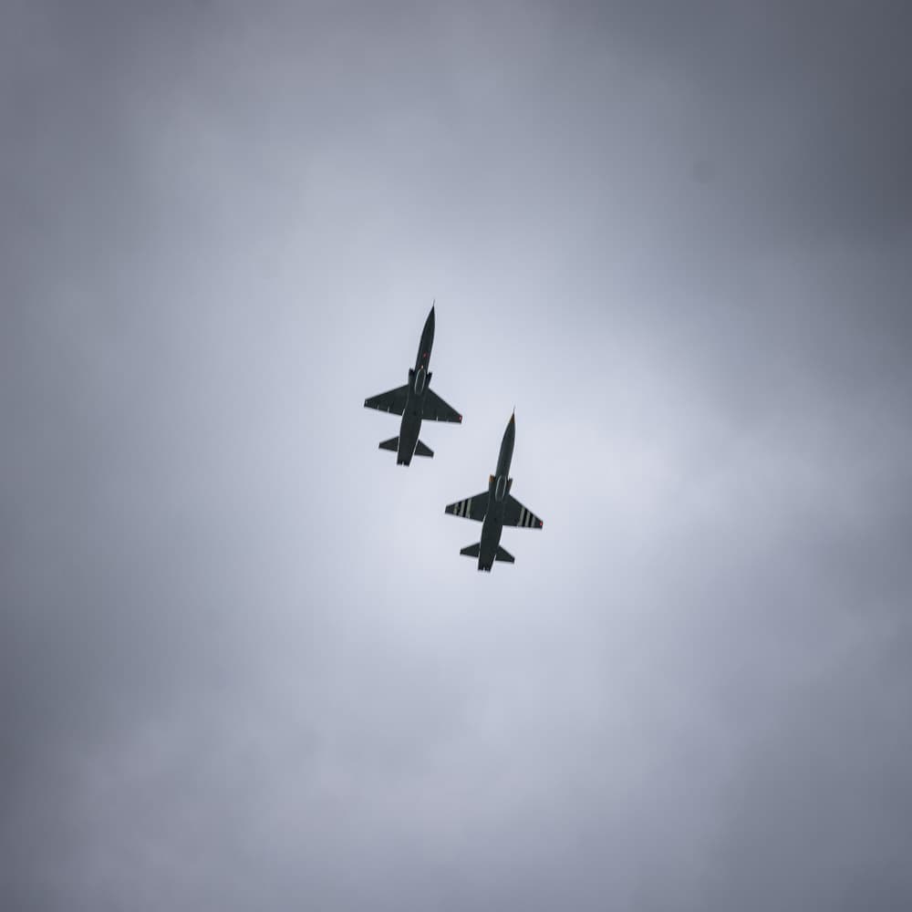 2 military jets in formation above