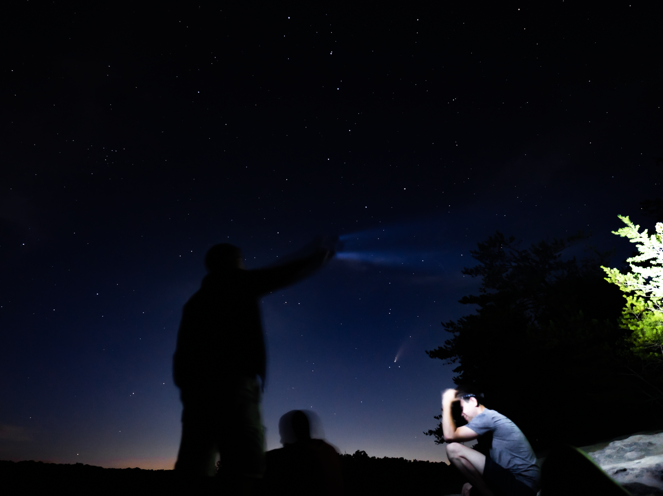 3 star gazer hikers under a night sky with the comet Neowise behind them