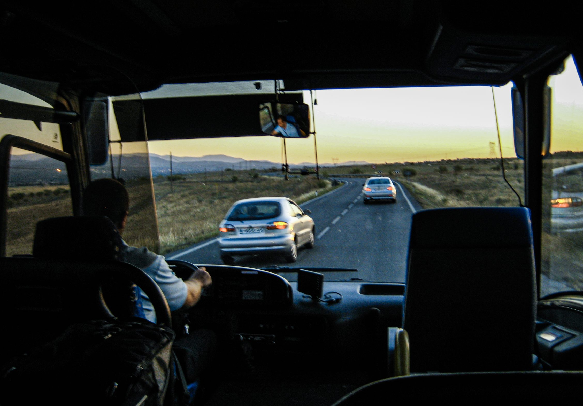 Looking out the front window of a bus as it cruises down a spanish highway early morning